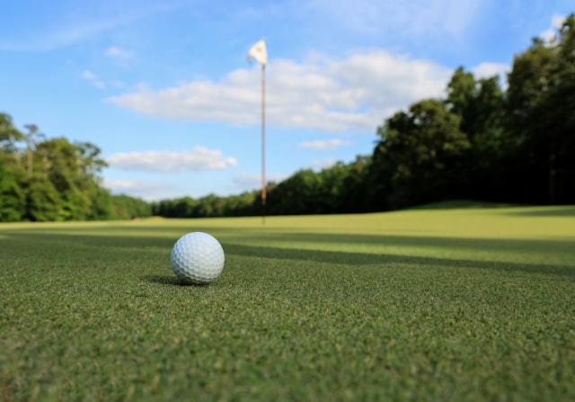 Symbolbild: Golfball auf dem Grün vor der Fahne