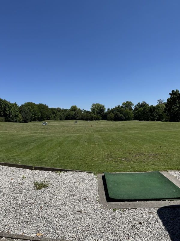 Abschlagmatte an einer Driving Range mit Blick auf das Übungsgelände