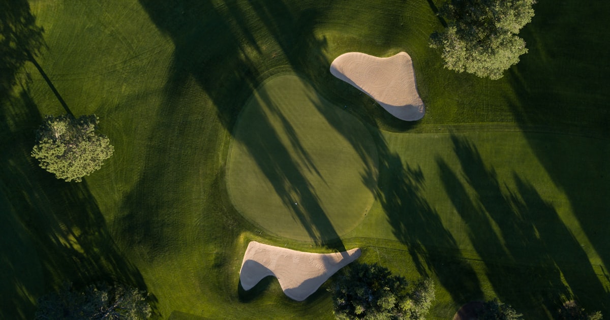 Symbolbild: Golfgrün mit zwei Bunkern aus der Vogelperspektive im Abendlicht