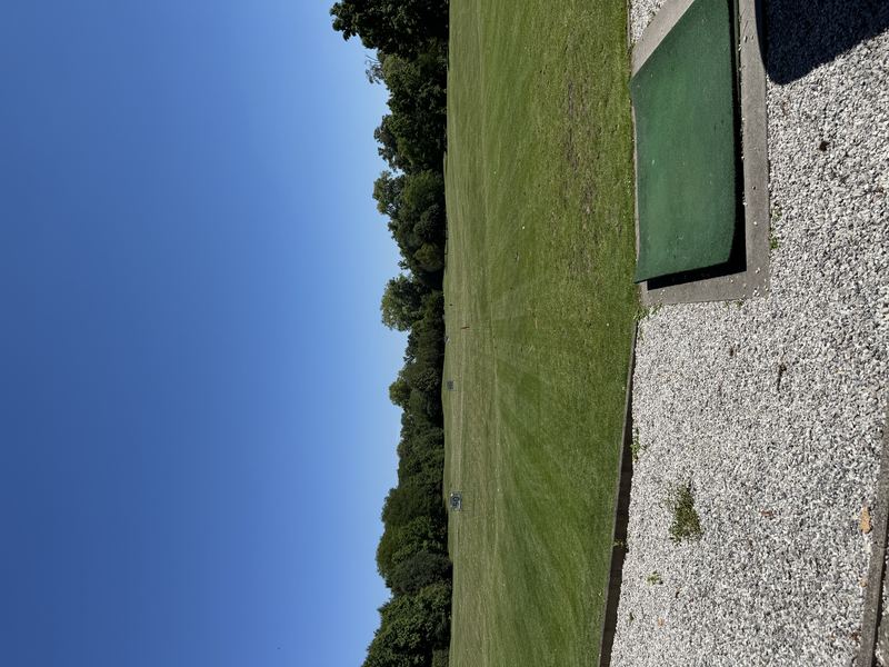 Abschlagmatte an einer Driving Range mit Blick auf das Übungsgelände