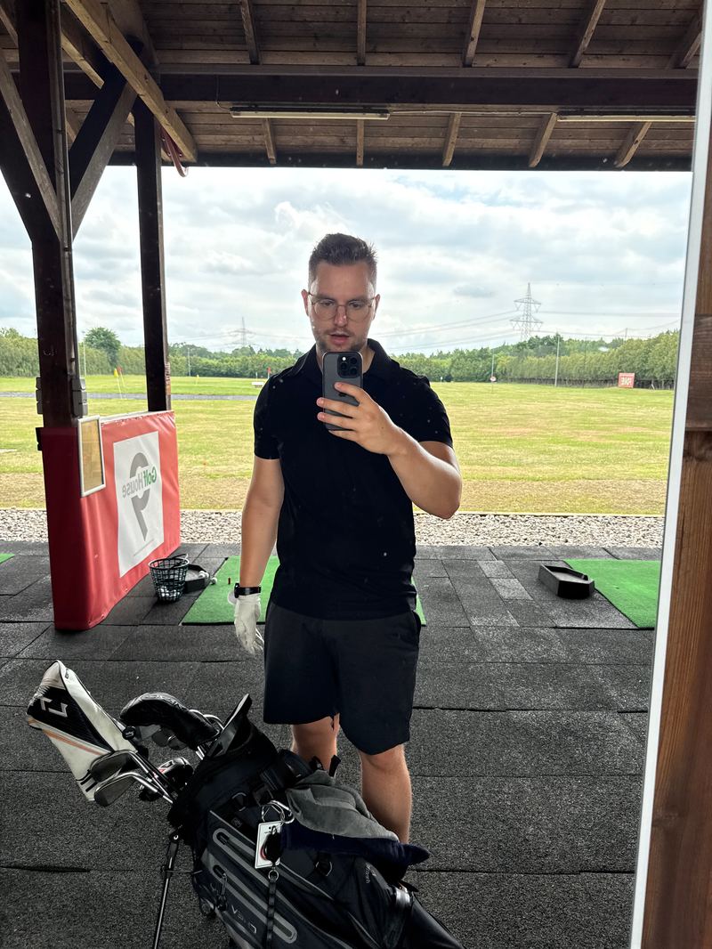 Sebastian Scholz mit Golfbag in einer überdachten Abschlagbox an der Driving Range
